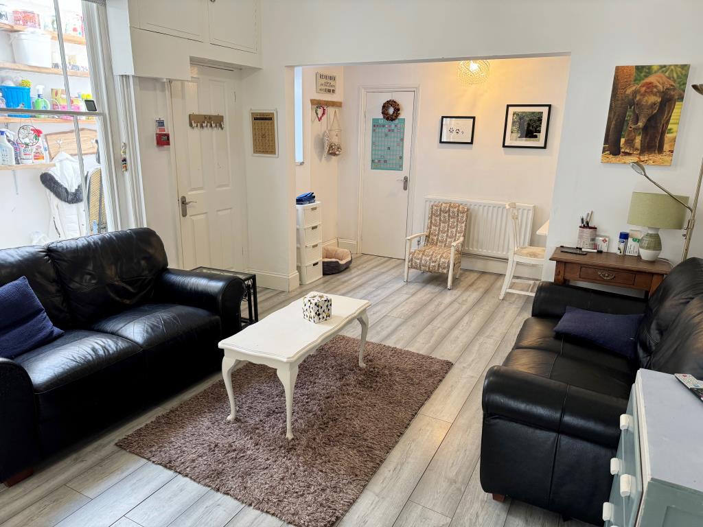 Lot: 102 - FREEHOLD GUEST HOUSE WITH 11 GUEST ROOMS AND SEPARATE OWNER'S ACCOMODATION - Ground floor room with painted walls wood effect flooring and furniture
